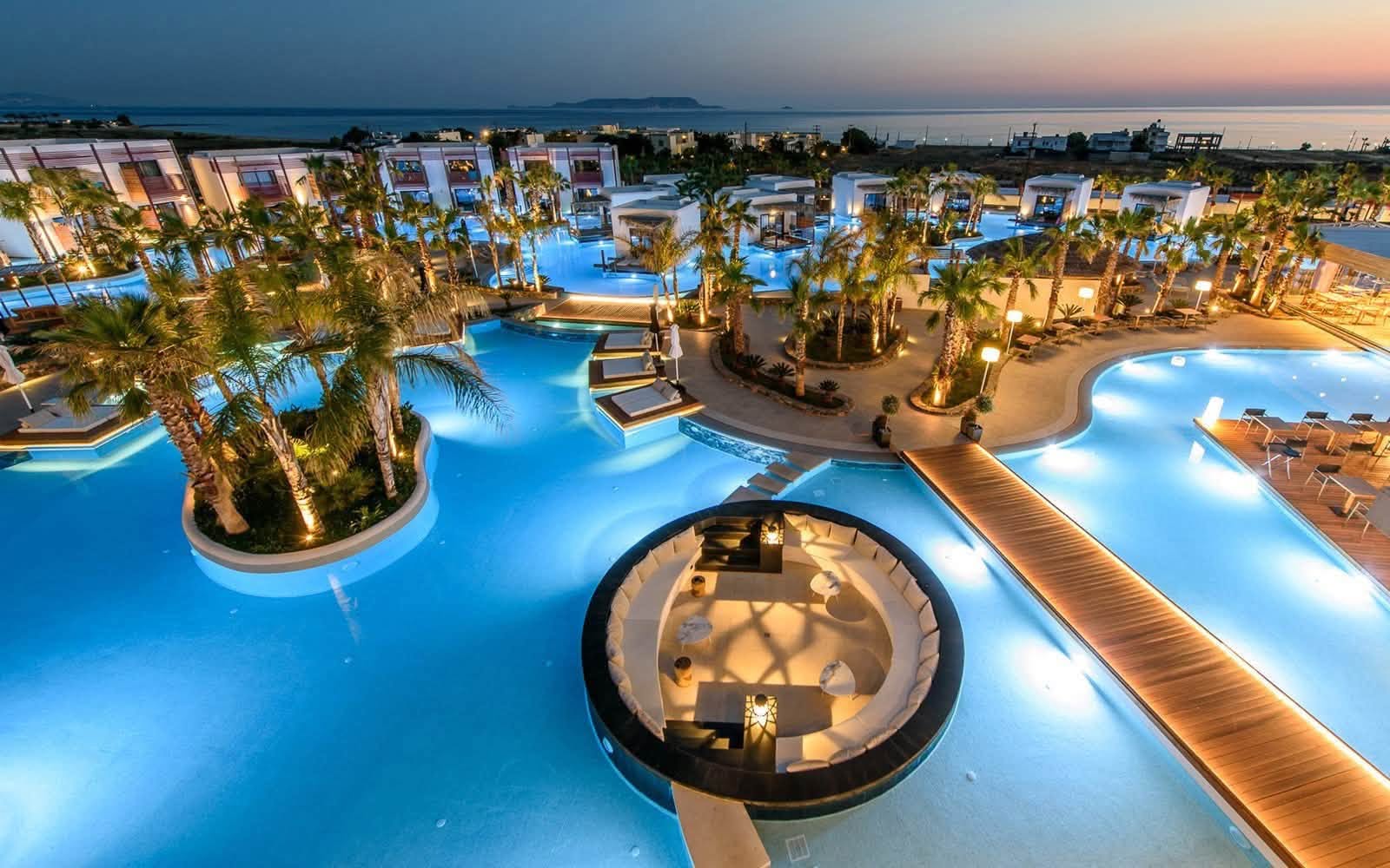 Stella Island resort lagoon pools illuminated at dusk